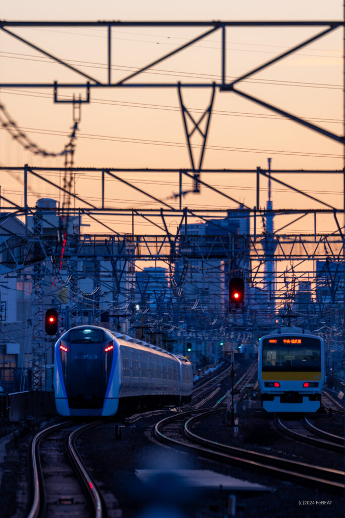 朝焼けの空にスカイツリーの見える中央快速線を吉祥寺から西荻窪へと走るE353系と中央緩行線を走るE231系