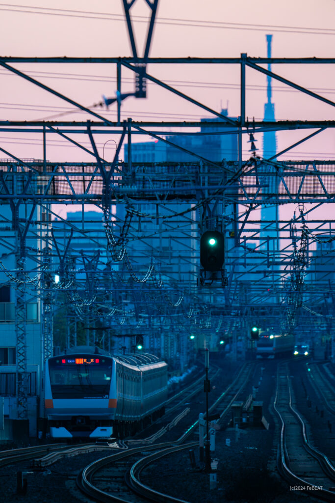 朝焼けの空にスカイツリーの見える中央快速線を吉祥寺から西荻窪へと走るE233系